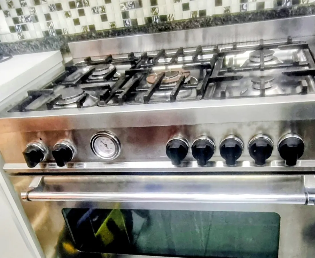 Fogão inox de seis bocas funcionando na cozinha do cliente